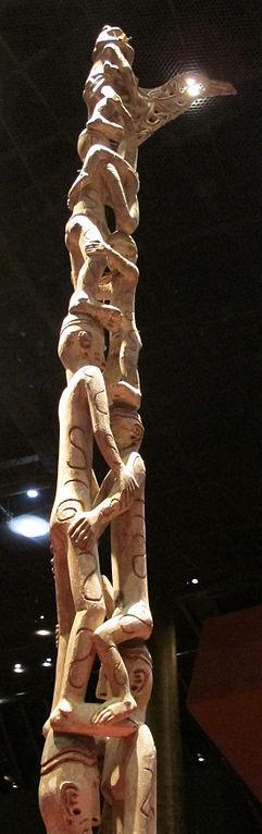 Take A Look At This Piece Of Art:Wood Carving Of People Standing On Top Of Each Other To Form A Pole.Carved